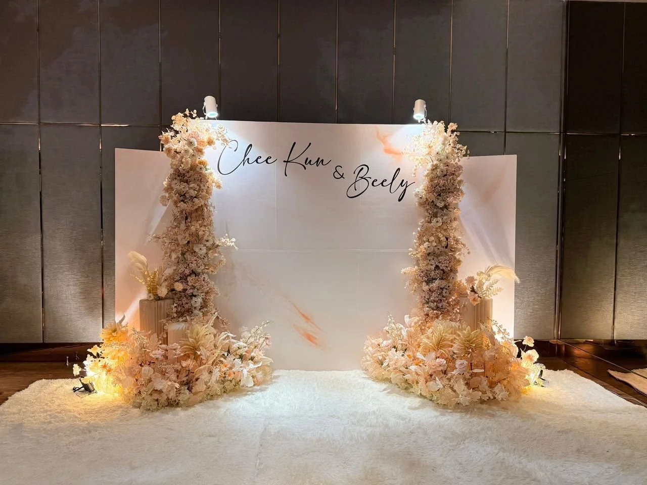 Soft neutral wedding backdrop with delicate floral arrangements and warm lighting