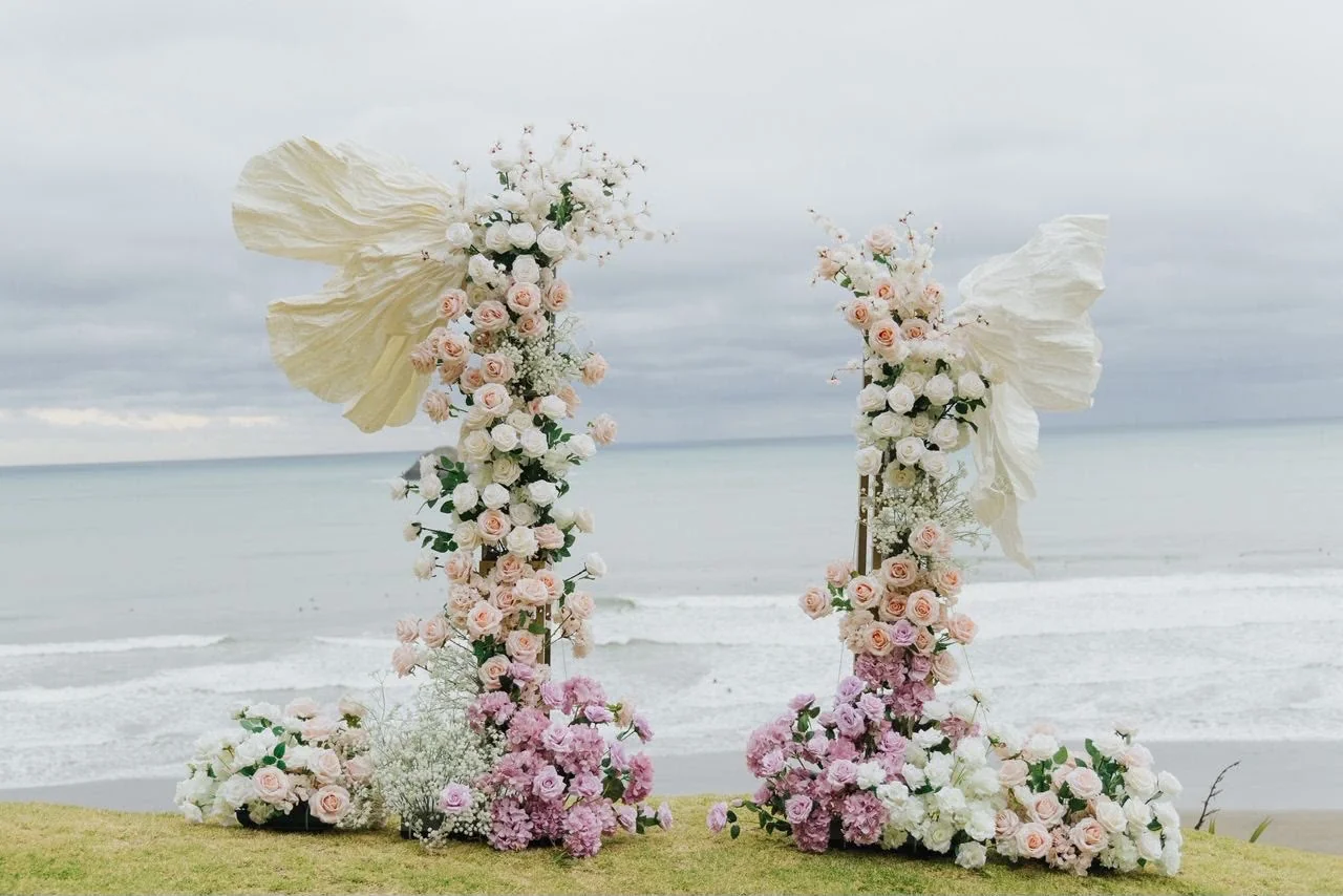 White and pink floral ceremony arch overlooking the sea